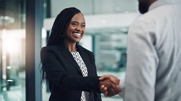 Businesswoman smiling while shaking hands with a man.