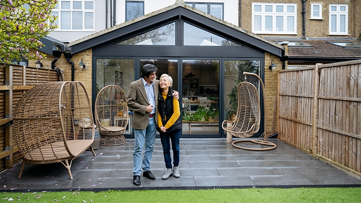 Couple standing in their new backyard smiling.