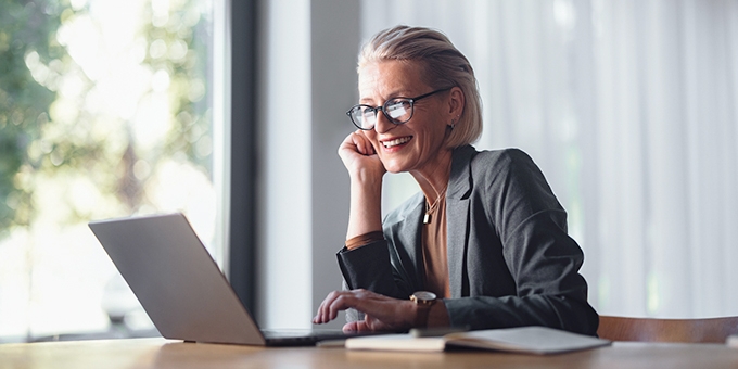 Business woman with laptop at desk in office.