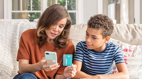 Mother with phone and debit card teaching child about finances.