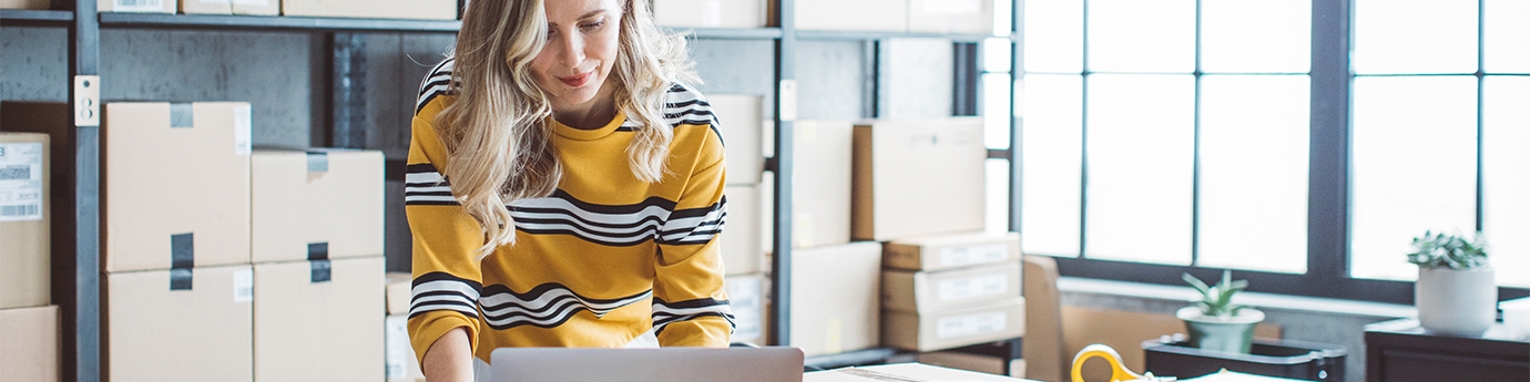 Female business owner on a laptop in a storage room.