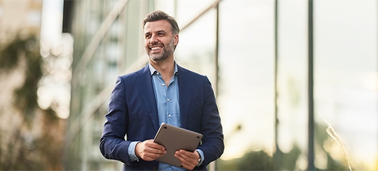 Happy businessman walking outside building.