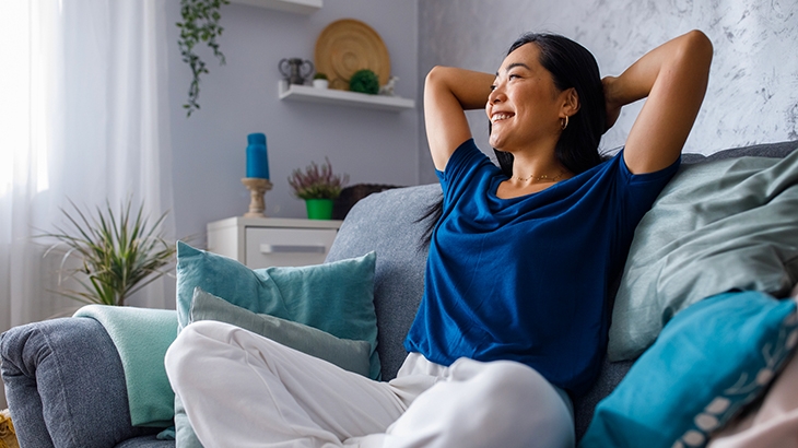 Woman on sofa relaxed, smiling, and daydreaming.