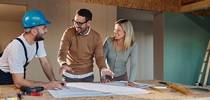 A couple with a contractor looking at their home remodeling plans.