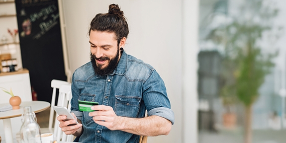 Man making a mobile credit card purchase in a cafe.