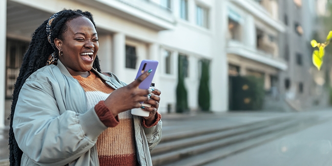 Woman laughing while looking at her mobile phone.