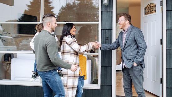  Una familia joven se encuentra con un agente inmobiliario frente a una nueva casa.