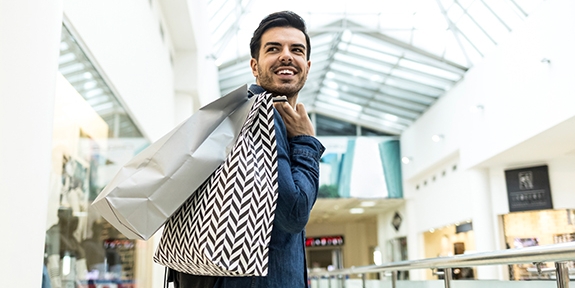 Man walking through a shopping mall with bags.