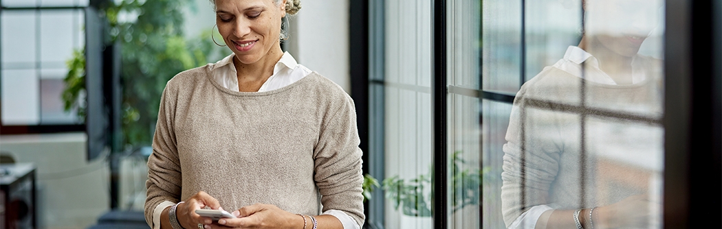 Businesswoman in office checking her mobile phone.