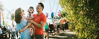 Parents holding their child while laughing at a carnival.