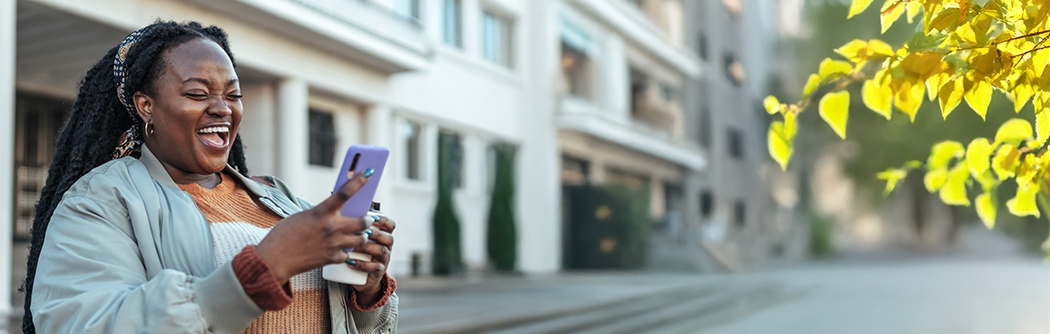 Woman laughing while looking at her mobile phone.