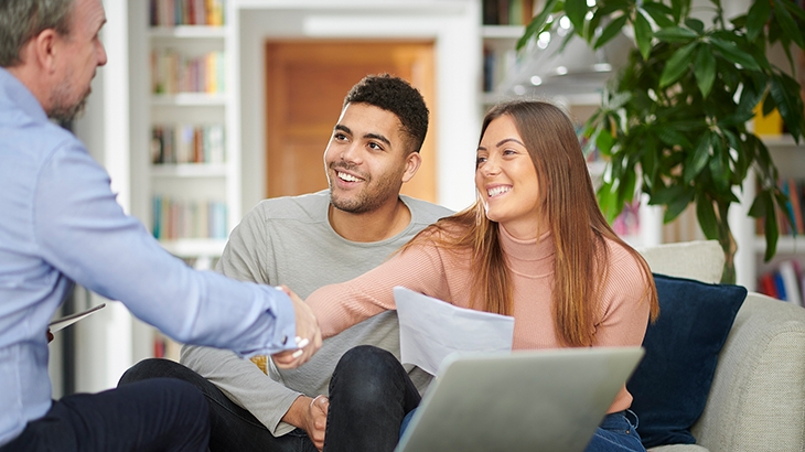 Couple shaking hands with financial advisor in office.