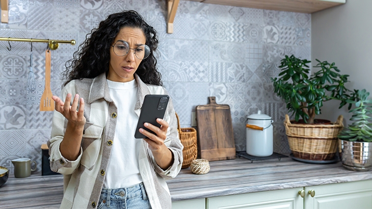 Woman looking at phone in frustration.