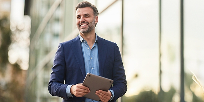 Happy businessman walking outside building.