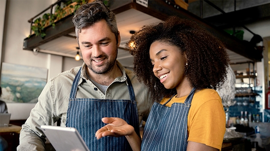 Coworkers in a cafe looking at a tablet together.