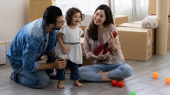 Padres e hija jugando con ukelele sentados en el suelo de la sala en casa.