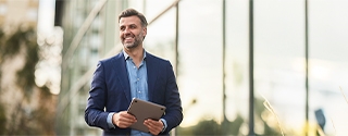 Happy businessman walking outside building.