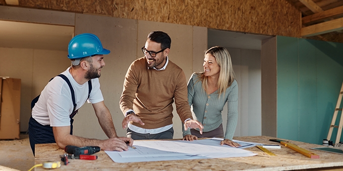 A couple with a contractor looking at their home remodeling plans.