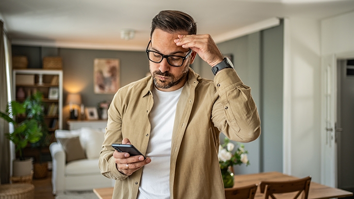 Man looking frustrated while looking at his mobile phone.