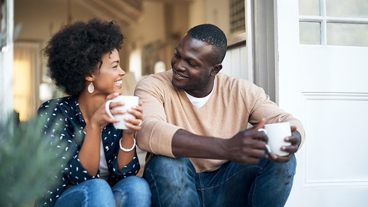 Happy young couple spending time together outside with coffee.